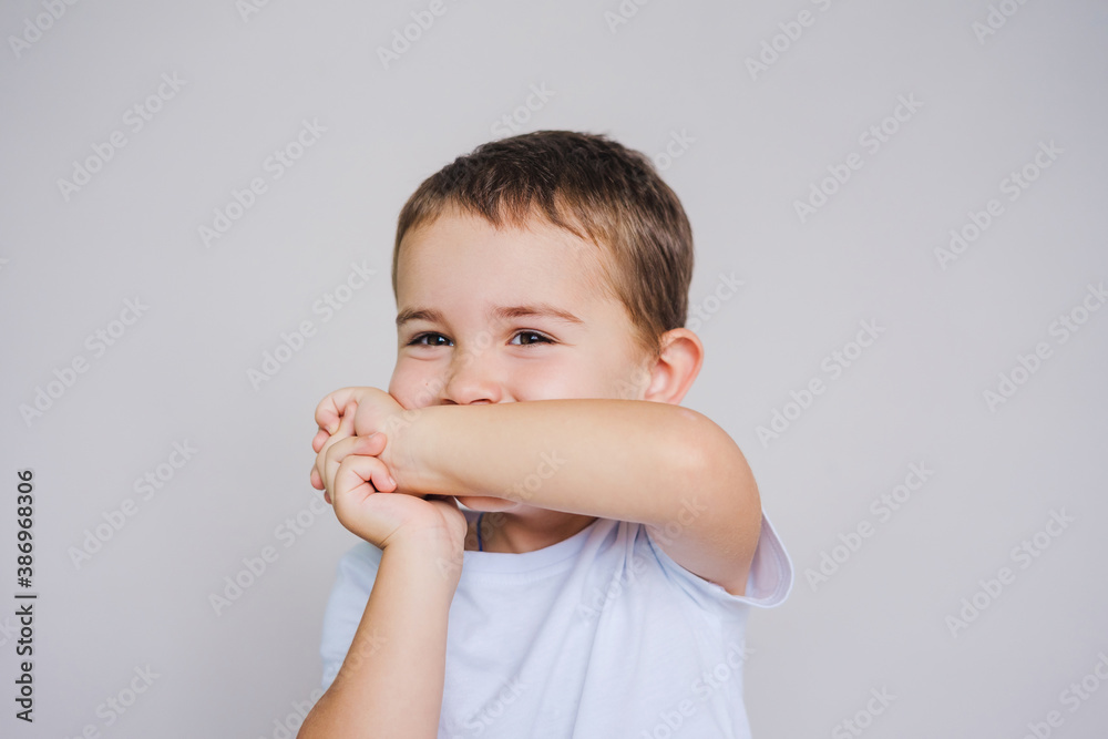 Little boy is embarrassed and laughs covering his face with his hands. Little boy is embarrassed and laughs covering his face with his hands.