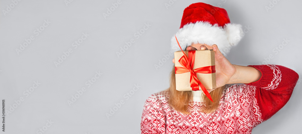 A woman in a Christmas sweater holds a gift box. Christmas presents. Christmas background. Banner. Copy space.