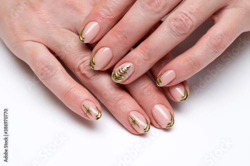 New Year's festive golden manicure with a painted tree and stars on short oval nails close-up on a white background. Gold casting. 
