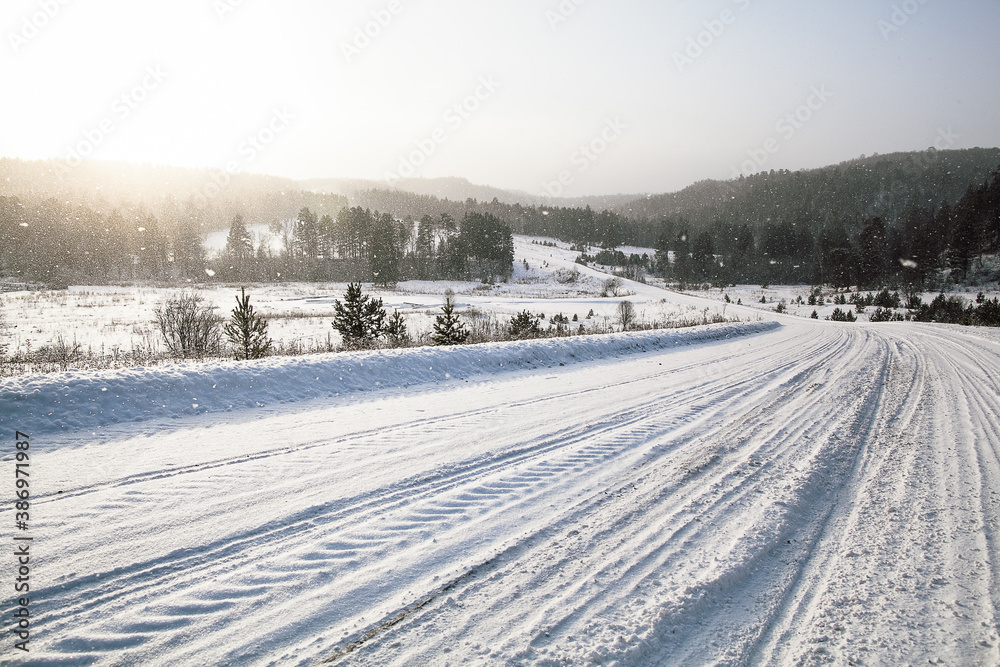 tire tracks in the snow, winter road, empty road in winter goes far to the horizon, covered with snow path, winter landscape
