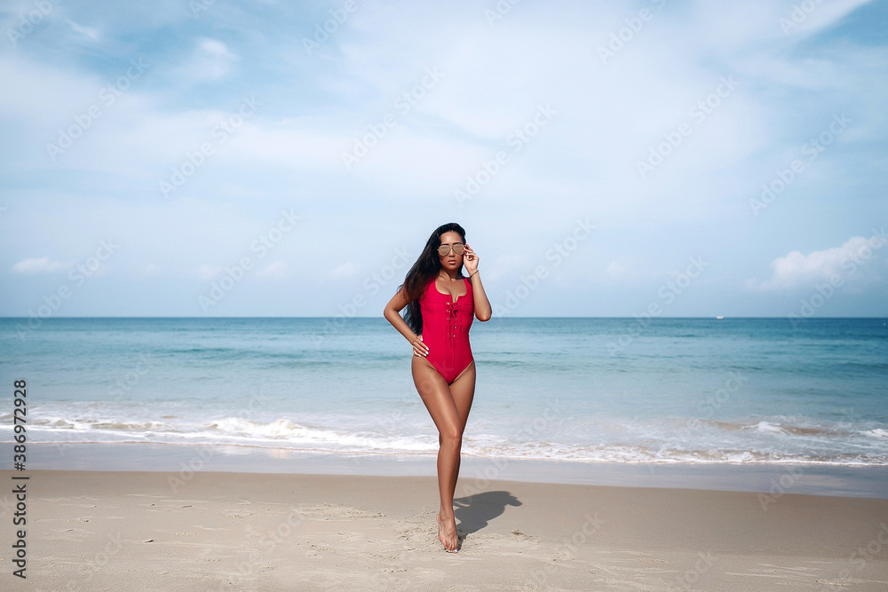 Beautiful asian woman in red swimsuit relaxing on beach during summer vacation travel Beautiful asian woman in red swimsuit relaxing on beach during summer vacation travel