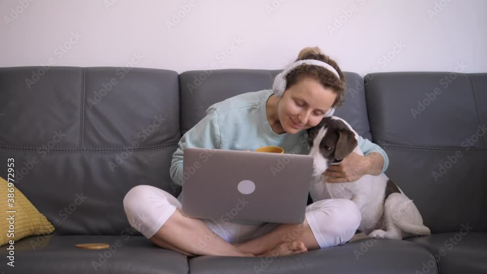 Front view of happy woman caressing lovely dog while staying at home with computer and coffee. Coronavirus restrictions concept. Front view of happy woman caressing lovely dog while staying at home with computer and coffee. Coronavirus restrictions concept.