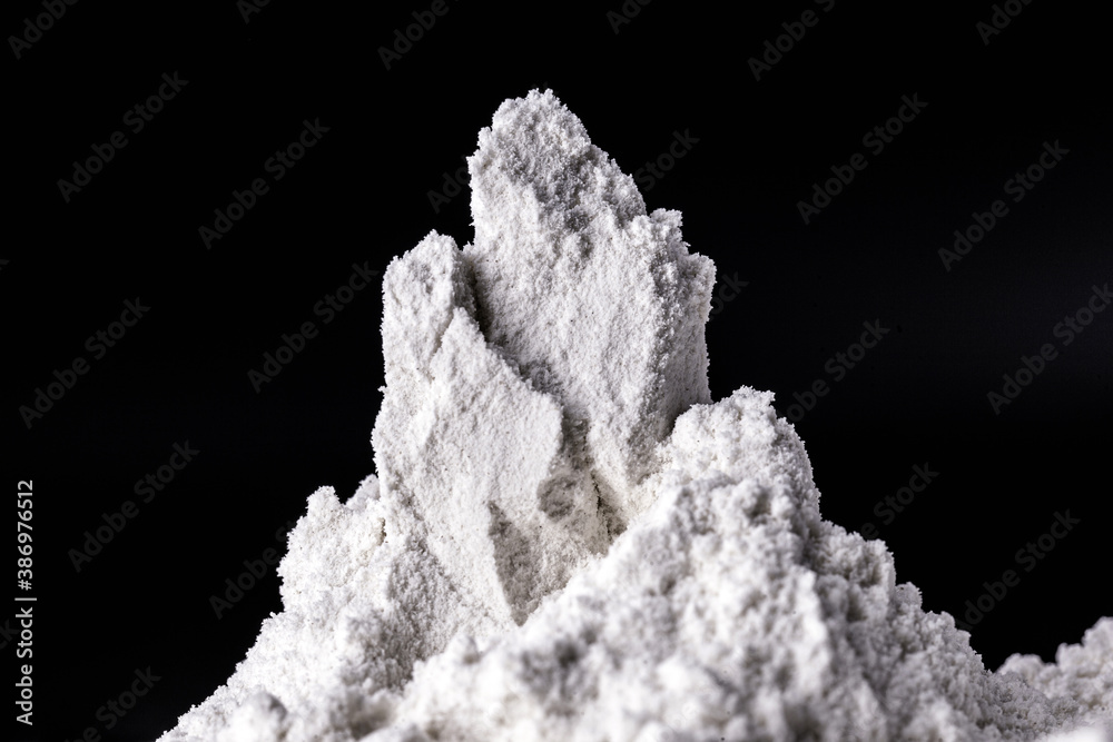 Obraz premium Kaolin on black isolated, powdered background. Kaolin is a mineral of inorganic constitution, chemically inert, extracted from deposits and processed in different granulometric bands. Used in the food
