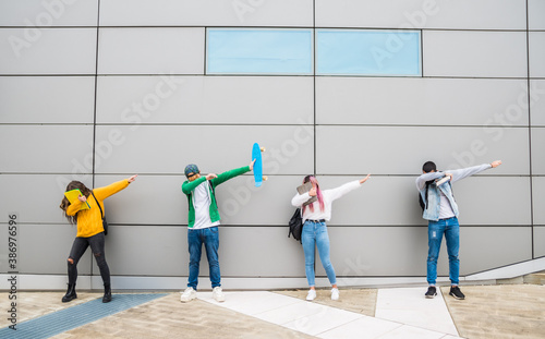 Funny young friends in casual clothes dancing dub dance on grey wall background. photo