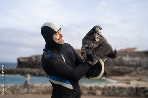 diver in suit holds his dog in his arms