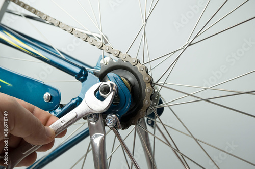 close up men's hands repair the wheel of a Bicycle, a man unscrews the wheel with a wrench