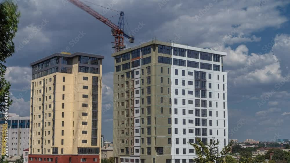 Crane and building construction site against blue sky aerial timelapse. Workers dyeing walls of new residential appartment house Crane and building construction site against blue sky aerial timelapse. Workers dyeing walls of new residential appartment house