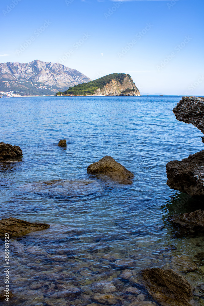 Seascape. Mountains and an island on the horizon. Stones and clear water of the adriatic sea