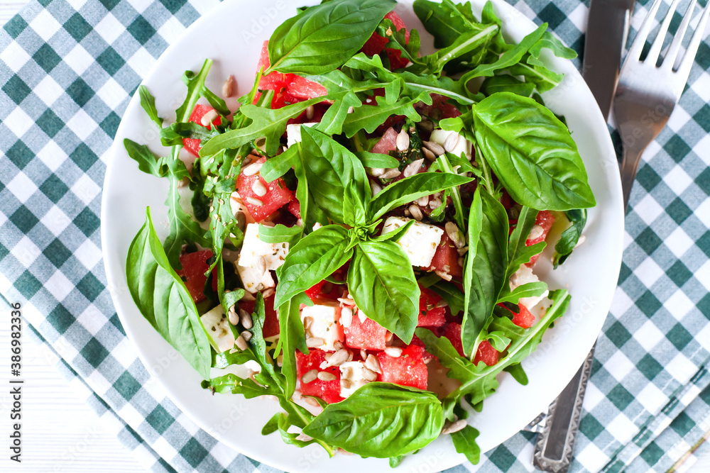 Fresh salad with watermelon, feta cheese, arugula, Sunflower seeds and basil leaves on plate. Close-up. Top view. Healthy food concept. Fresh salad with watermelon, feta cheese, arugula, Sunflower seeds and basil leaves on plate. Close-up. Top view. Healthy food concept.