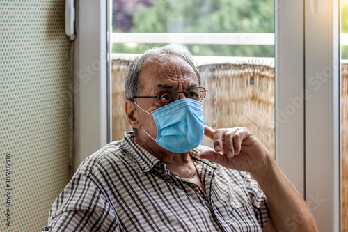 Face of elderly man wearing medical face mask, health safety concept. Aged pensioner man with gray hair wearing medical face mask looking away. Retired old man in protective face mask. Copy space. photo