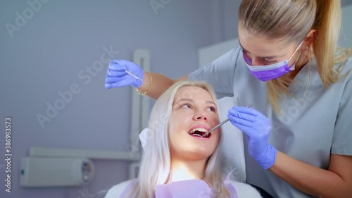 Dentist Examining Teeth With Medical Instruments Portrait Of Woman Checking His Teeth Professional Dentist Working With Gloves With Patients Teeth With An Open Mouth. Medical Stomatology Concept