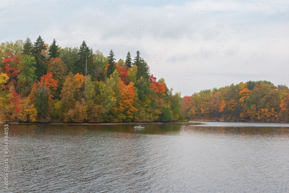 View to the boat with fishermen fishing in the Perse river in Koknese. Colorful red and yellow trees on the other river bank.
View to the boat with fishermen fishing in the Perse river in Koknese. Colorful red and yellow trees on the other river bank.