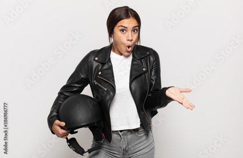 young hispanic woman feeling extremely shocked and surprised, anxious and panicking, with a stressed and horrified look