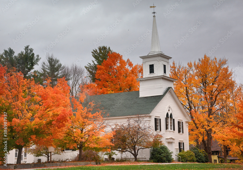 Autumn in scenic New England. Colorful orange and red maple trees and First Unitarion Congregational Church in rural Wilton Center, New Hampshire.
