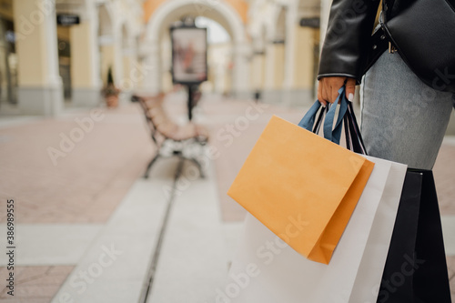 economical purchases in the store at discounts on sale. online shopping outlet, a woman holds several bags of different colors, orange, white, black in her hand