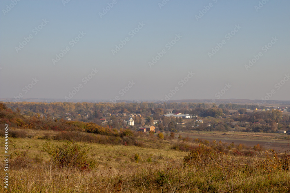 autumn landscape of the village,in the distance a village in autumn with a church at sunset