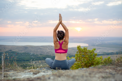 young pregnant woman does yoga outdoors. Yoga at sunset