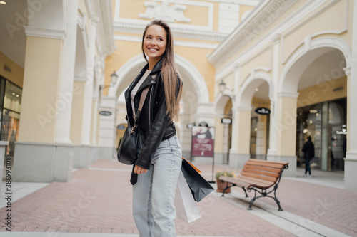 A beautiful confident woman of European appearance in a black leather jacket and blue jeans. sale of expensive items clothing in the outlet store online shopping.