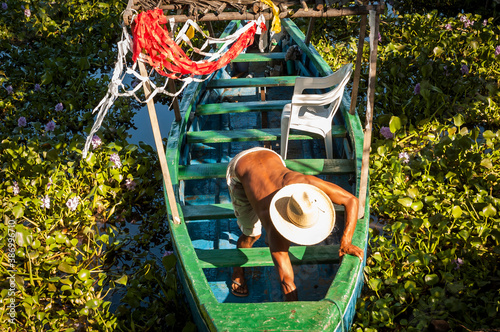 A shirtless man with a hat prepares his boat for a ride around the lagoon in Coyuca de Benitez, in the Mexican state of Guerrero, southern Mexico photo