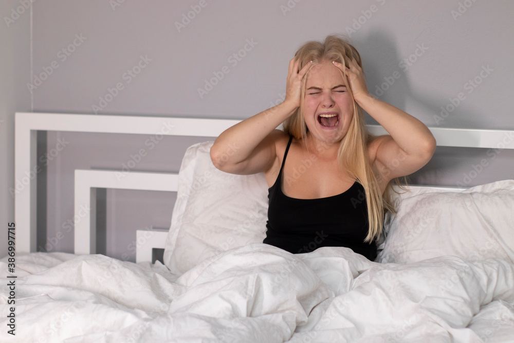 beautiful sad blonde burst into tears, crying, screaming in white bedroom. depressed people, problems concept. beautiful sad blonde burst into tears, crying, screaming in white bedroom. depressed people, problems concept.
