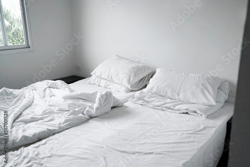 Cozy double beds in the morning. messy pillow and blanket on bed in white room. Lazy and relax days, Interior white room in cloudy day 