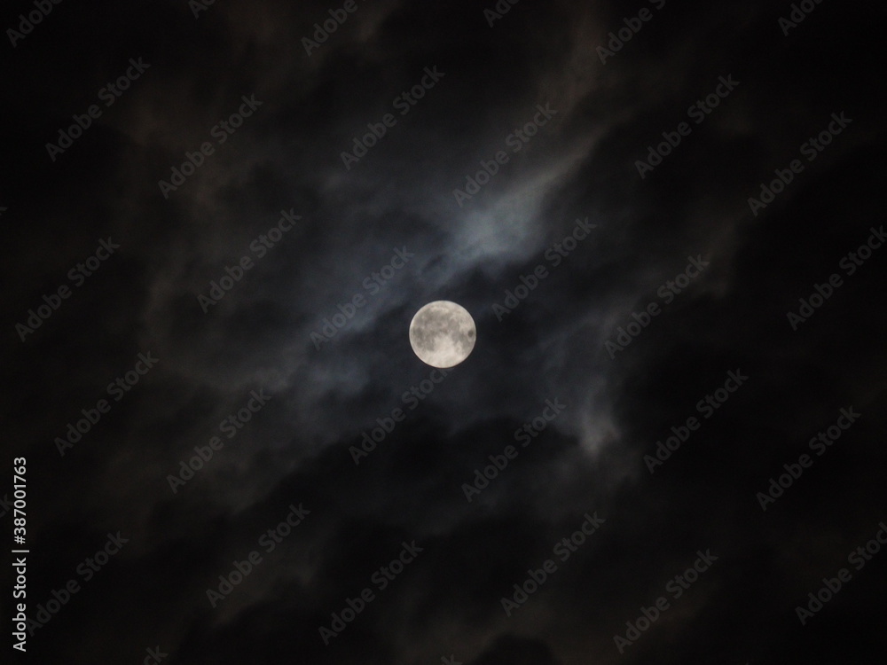 A huge moon in the clouds takes glory from a dim star. A huge moon in the clouds takes glory from a dim star.