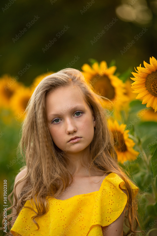 Cute teenage girl in yellow dress on the field with sunflowers Cute teenage girl in yellow dress on the field with sunflowers