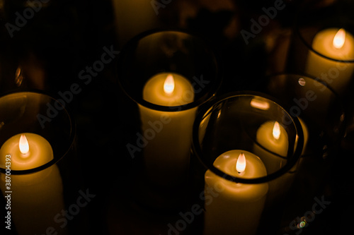 Romantic wedding display of wax candles glowing with small flames in glass vases centrepieces