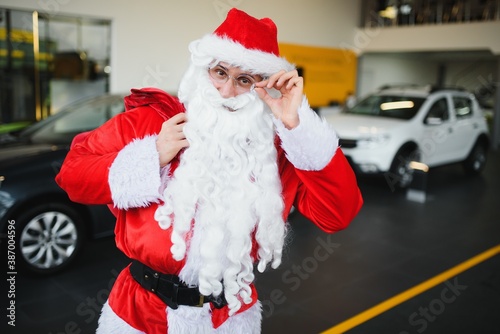 New car as a Christmas present. Santa Claus in the car showroom near a new car.