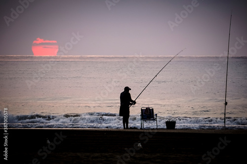 man fishing in the sea with the sun in the background