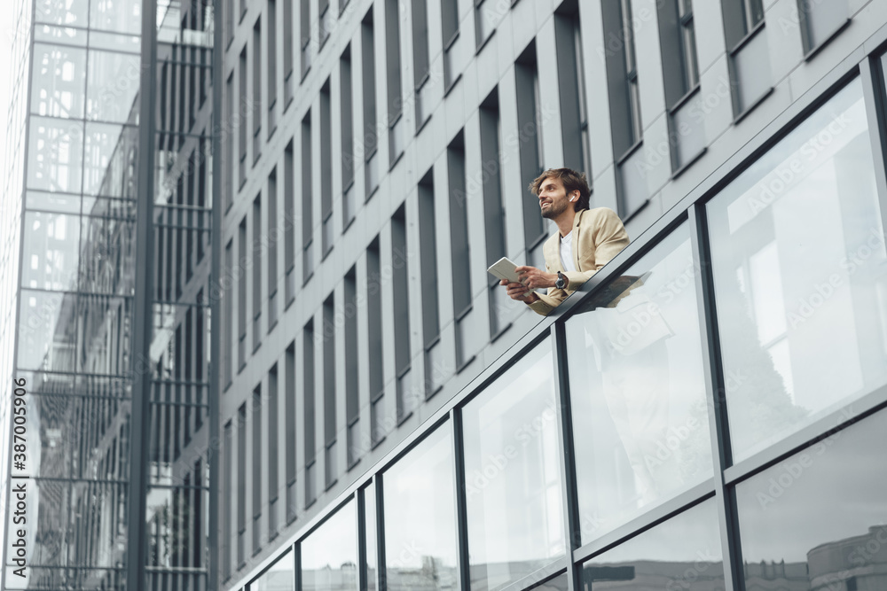 Low angle view of man standing outdoors with digital tablet Low angle view of man standing outdoors with digital tablet