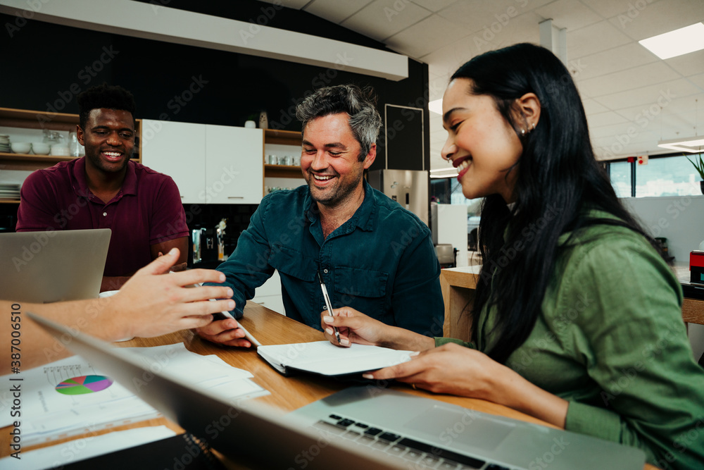 Diverse group gather to discuss work for the week sitting in office lounge before business meeting 