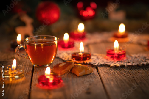 Winter ornamental decoration with burning candles on wooden rustic table. Mulled wine punch with gingerbread in foreground. Christmas holidays and New Year theme. Close-up