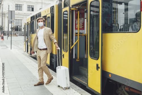 Photos Businessman in medical mask getting off yellow tramway