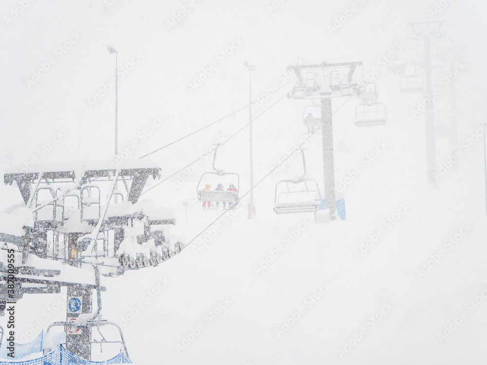 A chair lift carries people up during snowfstorm in heavy fog A chair lift carries people up during snowfstorm in heavy fog