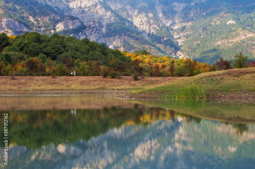 Mountain lake. Magnificent autumn landscape with mountains, lake and forest. Beautiful reflection of mountains in the lake.