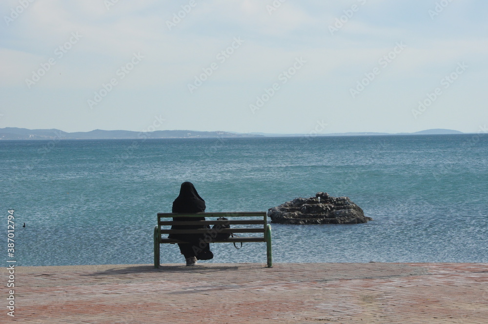 a woman with veiling watching the sea a woman with veiling watching the sea