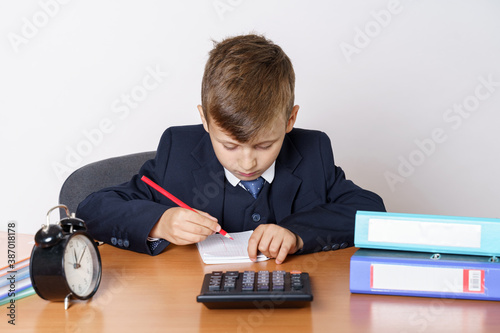 The young businessman is tired of work, draws. On the table is a calculator, next to a mini shopping trolley, a clock and folders with reports.