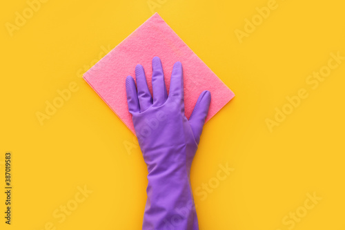 Employee hand in rubber protective glove with micro fiber cloth on yellow background. Spring general or regular clean up. Top view