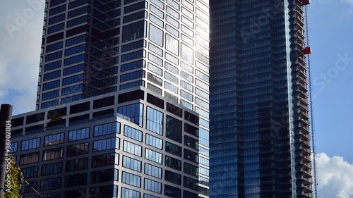 Blue curtain wall made of toned glass and steel constructions under blue sky. A fragment of a building.