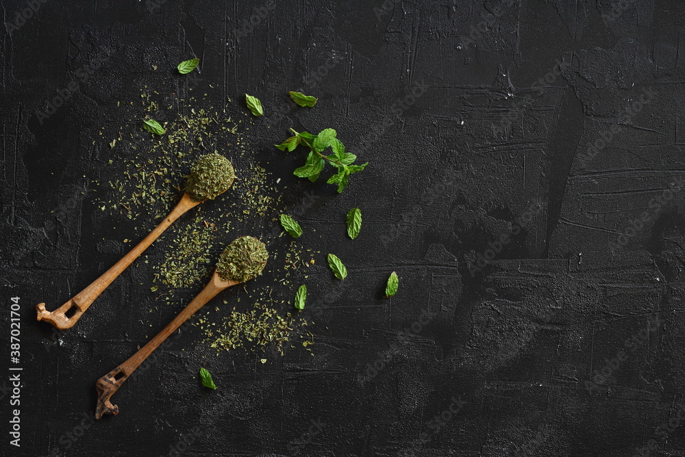 mint on wooden spoon isolated on black background. herbs and spices on a wooden background mint on wooden spoon isolated on black background. herbs and spices on a wooden background