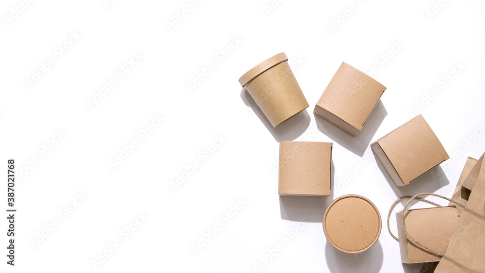 Cardboard containers for food, drinks and items drop out of the craft bag.  Isolated on white background, top view. Copy space. Delivery, takeaway food, eco-friendly packaging concept. Nobody.
