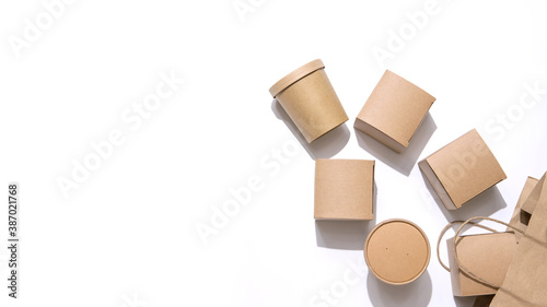 Cardboard containers for food, drinks and items drop out of the craft bag.  Isolated on white background, top view. Copy space. Delivery, takeaway food, eco-friendly packaging concept. Nobody.
