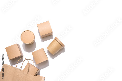 Cardboard containers for food, drinks and items drop out of the craft bag.  Isolated on white background, top view. Copy space. Delivery, takeaway food, eco-friendly packaging concept. Nobody.
