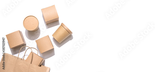 Cardboard containers for food, drinks and items drop out of the craft bag.  Isolated on white background, top view. Copy space. Delivery, takeaway food, eco-friendly packaging concept. Nobody.
