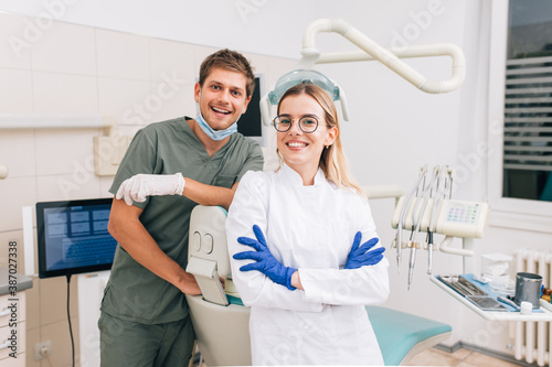 Portrait of dentist with young female assistant in uniform at the dental office