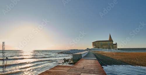 Fototapeta Naklejka Na Ścianę i Meble -  The church of Madonna of the Angel in Caorle, seen from the pier of the east beach at sunrise at the end of summer