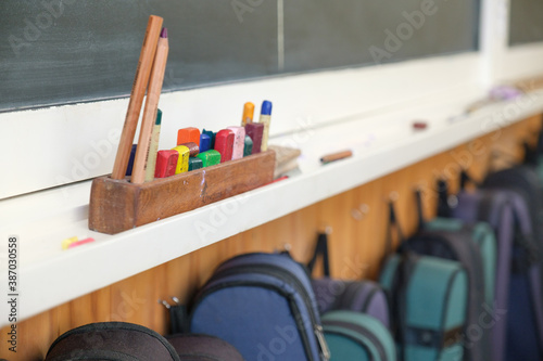 Blackboard with crayons and pencil and line of violin cases hung below photo