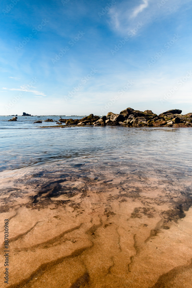 A rock formation in the beach at low tide with sky reflections