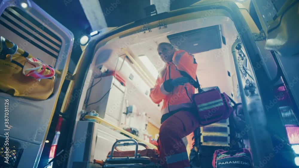 Team of EMS Paramedics Quickly Jump Out from Ambulance Vehicle. Female Doctor Takes First Aid Kit. Emergency Care Assistants Arrived on the Scene of a Traffic Accident on a Street at Night.